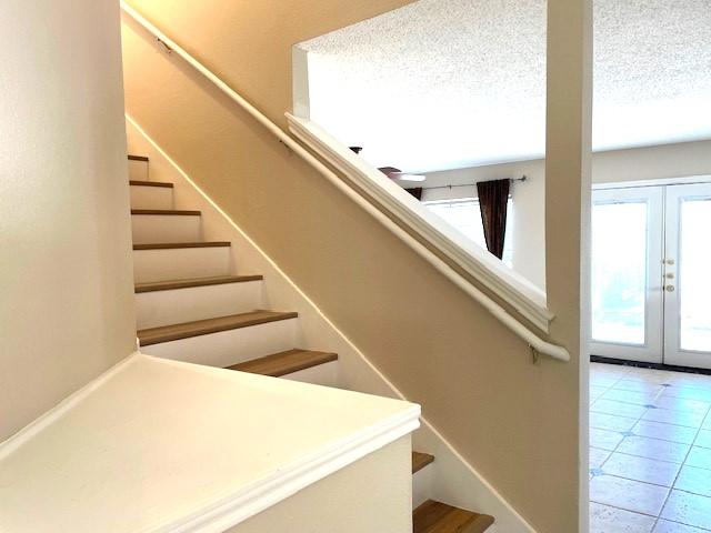 2727 High Point Dr, Round Rock, TX 78664 - stairway with healthy amount of natural light, french doors, tile patterned floors, and a textured ceiling