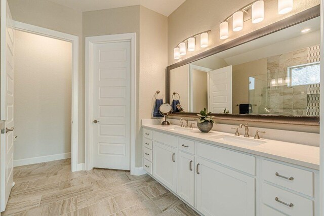 305 Dashing Sycamore St, San Marcos, TX 78666 - bathroom with tiled shower, double vanity, and baseboards