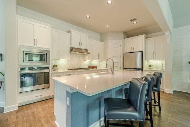 305 Dashing Sycamore St, San Marcos, TX 78666 - kitchen featuring stainless steel appliances, a sink, wood finished floors, white cabinets, and recessed lighting