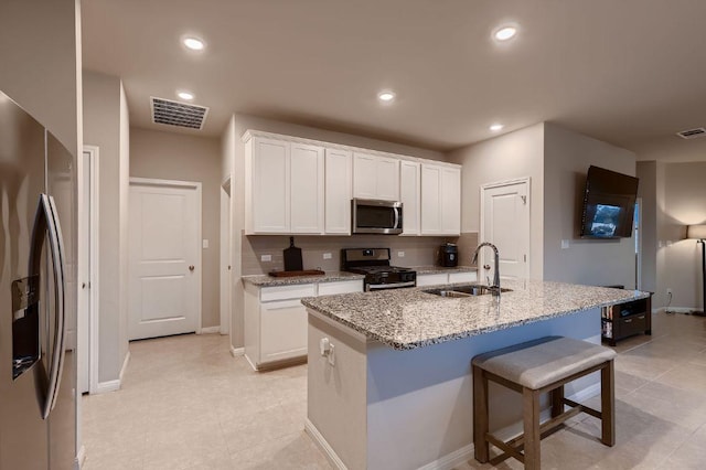 233 Mcfarland St, Georgetown, TX 78628 - kitchen featuring appliances with stainless steel finishes, a sink, white cabinetry, light stone counters, and recessed lighting