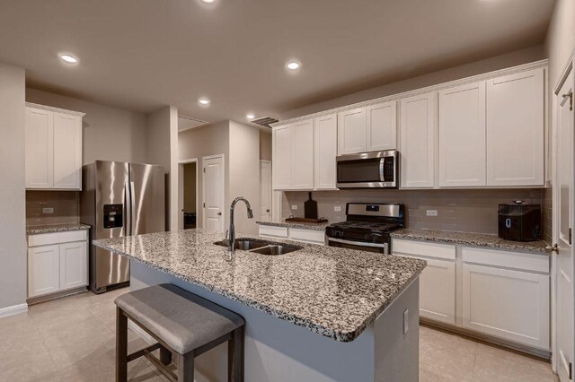 233 Mcfarland St, Georgetown, TX 78628 - kitchen featuring appliances with stainless steel finishes, a sink, a kitchen island with sink, backsplash, and white cabinets