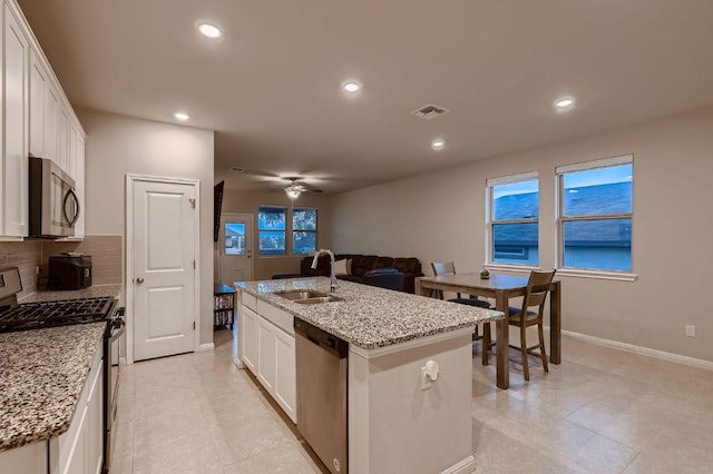 233 Mcfarland St, Georgetown, TX 78628 - kitchen featuring stainless steel appliances, a sink, white cabinets, recessed lighting, and a kitchen island with sink