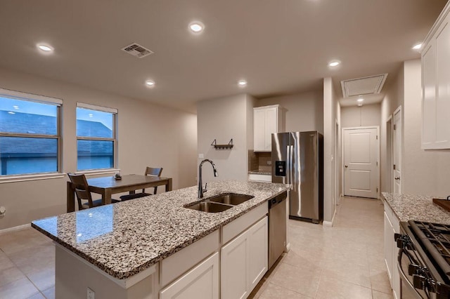 233 Mcfarland St, Georgetown, TX 78628 - kitchen featuring a sink, stainless steel appliances, white cabinets, light stone countertops, and recessed lighting