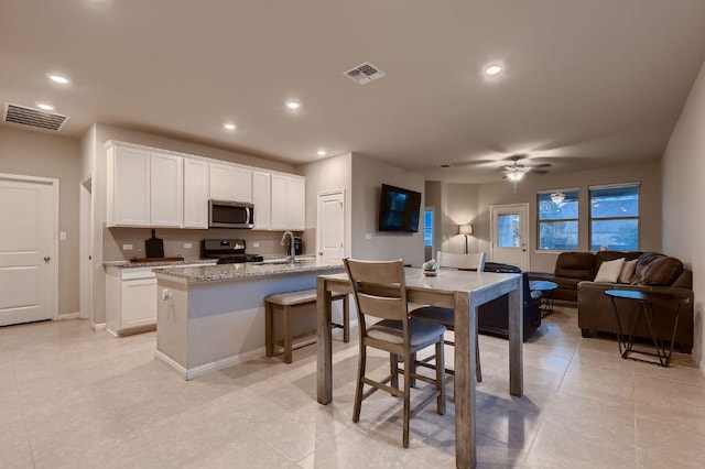 233 Mcfarland St, Georgetown, TX 78628 - kitchen featuring stainless steel appliances, a ceiling fan, open floor plan, white cabinets, and recessed lighting