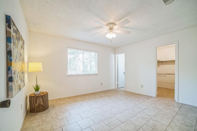 409 Mountain Laurel Dr, Cedar Park, TX 78613 - unfurnished bedroom with a spacious closet, a textured ceiling, light tile patterned floors, a ceiling fan, and a closet