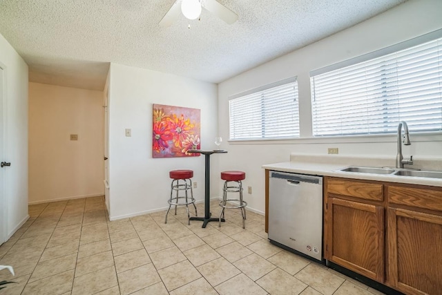 409 Mountain Laurel Dr, Cedar Park, TX 78613 - kitchen with stainless steel dishwasher, a sink, ceiling fan, brown cabinetry, and a textured ceiling