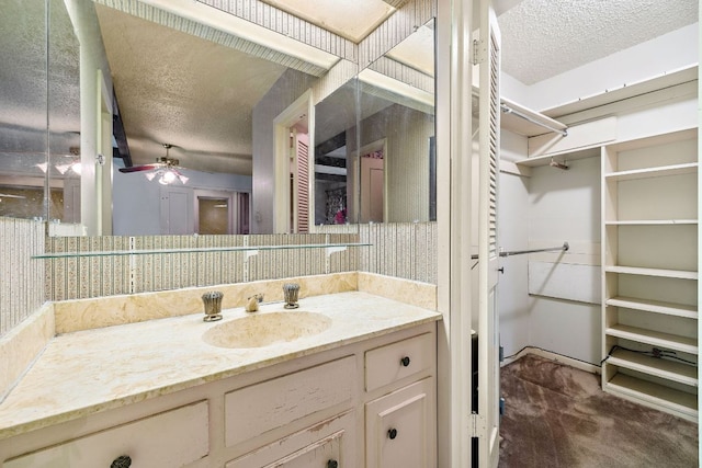 8400 Shenandoah Dr, Austin, TX 78753 - bathroom featuring a textured ceiling, vanity, a ceiling fan, and a spacious closet