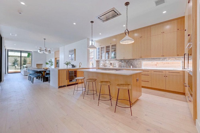 1601 Woodlawn Blvd, Austin, TX 78703 - kitchen with light brown cabinetry, decorative backsplash, a center island, light countertops, and a breakfast bar area