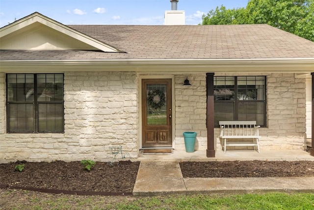 506 S Main St, Thrall, TX 76578 - property entrance featuring a shingled roof, stone siding, a chimney, and a porch