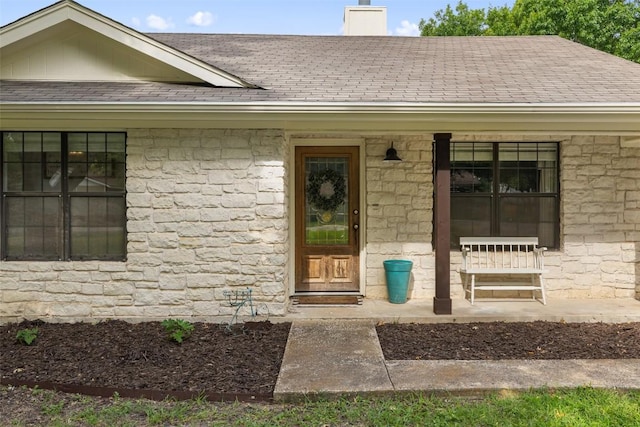 506 S Main St, Thrall, TX 76578 - view of exterior entry with stone siding, a chimney, a shingled roof, and covered porch
