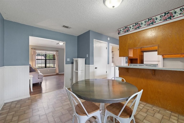 506 S Main St, Thrall, TX 76578 - dining space with brick patterned floors, a textured ceiling, a ceiling fan, and wainscoting