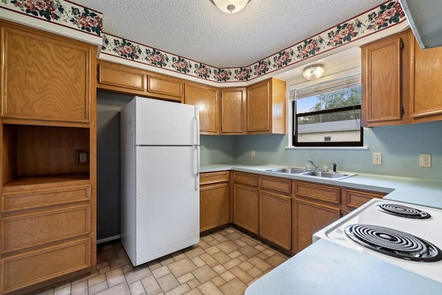 506 S Main St, Thrall, TX 76578 - kitchen with freestanding refrigerator, a sink, light countertops, brown cabinets, and a textured ceiling