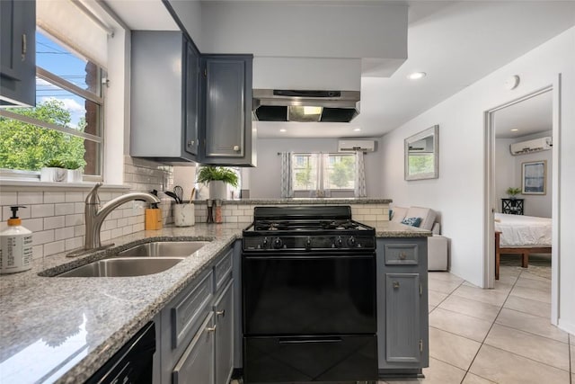 1715 Bluebonnet Ln, Austin, TX 78704 - kitchen featuring black gas range oven, a sink, under cabinet range hood, a wall unit AC, and a peninsula