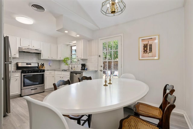1715 Bluebonnet Ln, Austin, TX 78704 - kitchen featuring appliances with stainless steel finishes, under cabinet range hood, decorative backsplash, light wood-style floors, and lofted ceiling