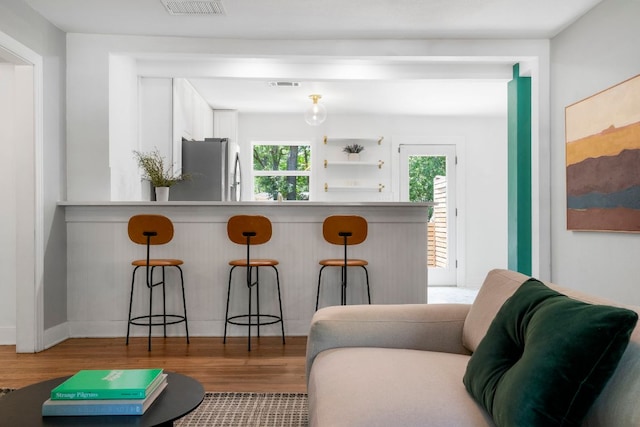 1505 Palo Duro Rd, Austin, TX 78757 - kitchen featuring freestanding refrigerator, wood finished floors, a kitchen bar, white cabinets, and baseboards