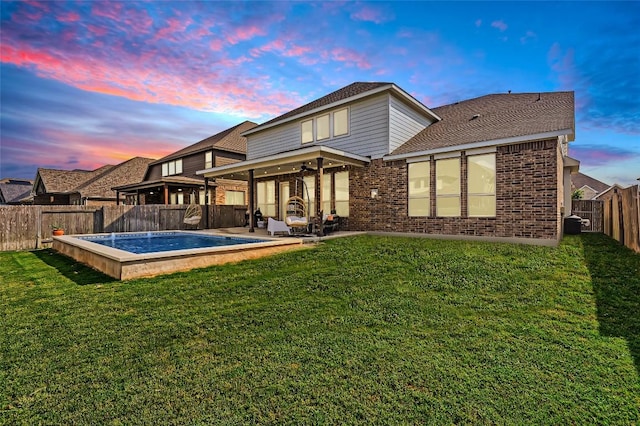 4116 Brean Down Rd, Pflugerville, TX 78660 - back of house at dusk featuring brick siding, ceiling fan, a patio area, and roof with shingles