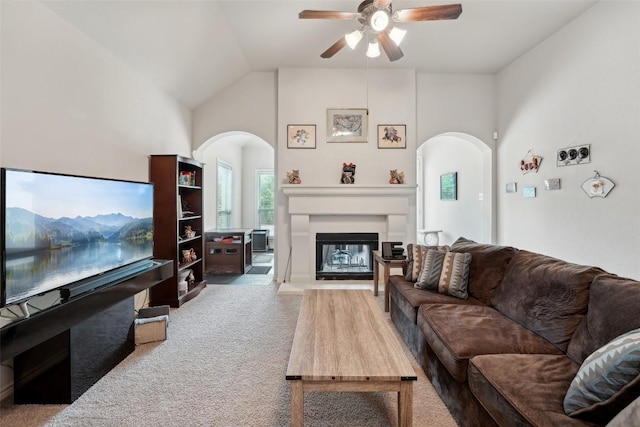 722 Tom Kite Dr, Round Rock, TX 78664 - carpeted living area featuring arched walkways, a ceiling fan, a glass covered fireplace, and vaulted ceiling