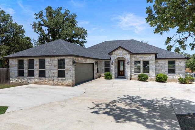 127 Medlar Dr, Cedar Creek, TX 78612 - french country style house with stone siding, a garage, driveway, and a shingled roof