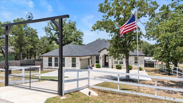 127 Medlar Dr, Cedar Creek, TX 78612 - view of front of home with stone siding, a garage, a fenced front yard, driveway, and a gate