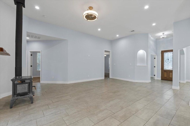 127 Medlar Dr, Cedar Creek, TX 78612 - unfurnished living room featuring a wood stove, recessed lighting, baseboards, and a high ceiling