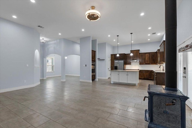 127 Medlar Dr, Cedar Creek, TX 78612 - kitchen featuring stainless steel refrigerator with ice dispenser, open floor plan, arched walkways, a sink, and a center island
