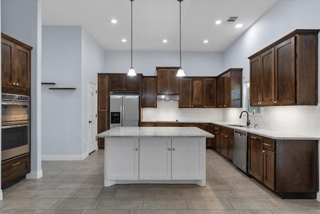127 Medlar Dr, Cedar Creek, TX 78612 - kitchen featuring appliances with stainless steel finishes, backsplash, dark brown cabinets, a center island, and recessed lighting