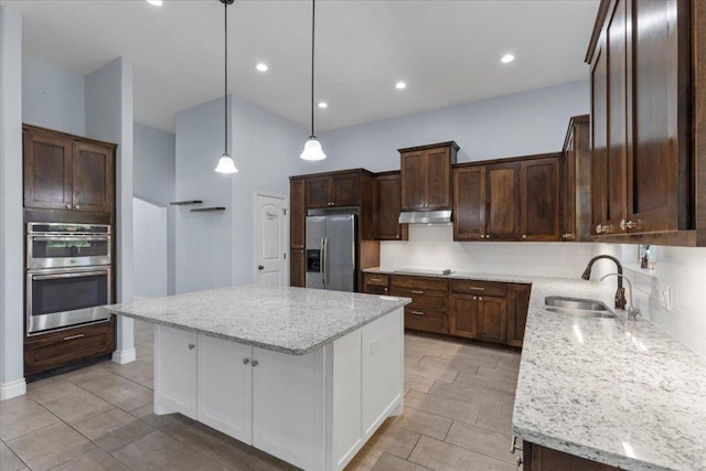 127 Medlar Dr, Cedar Creek, TX 78612 - kitchen with stainless steel appliances, a sink, under cabinet range hood, tasteful backsplash, and a center island
