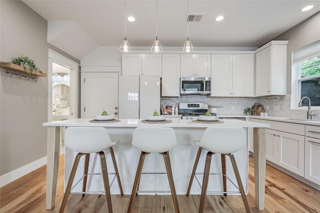 5512 Duval St Unit 2, Austin, TX 78751 - kitchen with appliances with stainless steel finishes, tasteful backsplash, light countertops, a kitchen bar, and white cabinets