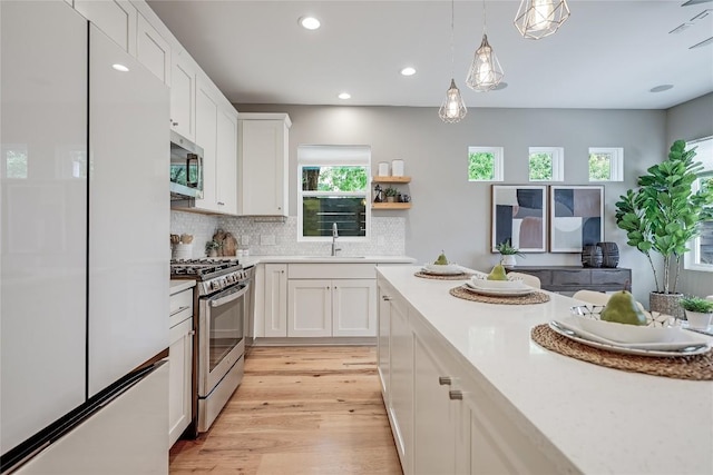 5512 Duval St Unit 2, Austin, TX 78751 - kitchen with stainless steel appliances, a sink, light wood finished floors, light countertops, and white cabinetry