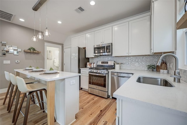 5512 Duval St Unit 2, Austin, TX 78751 - kitchen featuring stainless steel appliances, a sink, decorative backsplash, light wood-style flooring, and a kitchen island
