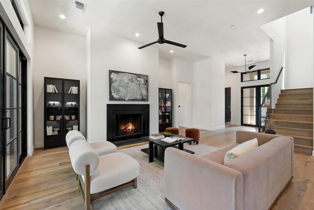 5218 Valley Oak Dr, Austin, TX 78731 - living area featuring light wood finished floors, a ceiling fan, a lit fireplace, recessed lighting, and stairway