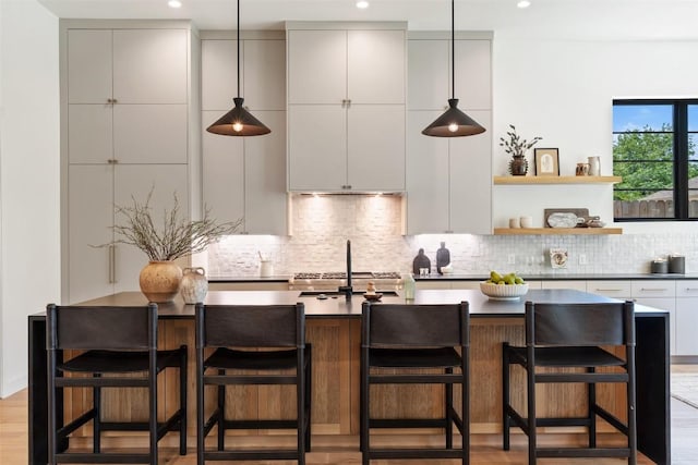 5218 Valley Oak Dr, Austin, TX 78731 - kitchen with dark countertops, tasteful backsplash, modern cabinets, a center island with sink, and recessed lighting