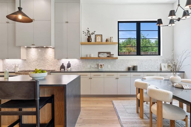 5218 Valley Oak Dr, Austin, TX 78731 - kitchen with dark countertops, stainless steel gas cooktop, light wood-type flooring, and decorative backsplash