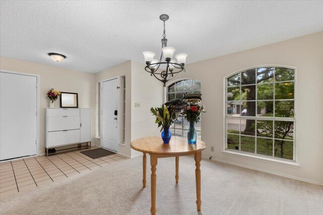 601 Wagon Wheel Trl, Pflugerville, TX 78660 - carpeted dining room with a chandelier, a textured ceiling, baseboards, and tile patterned floors