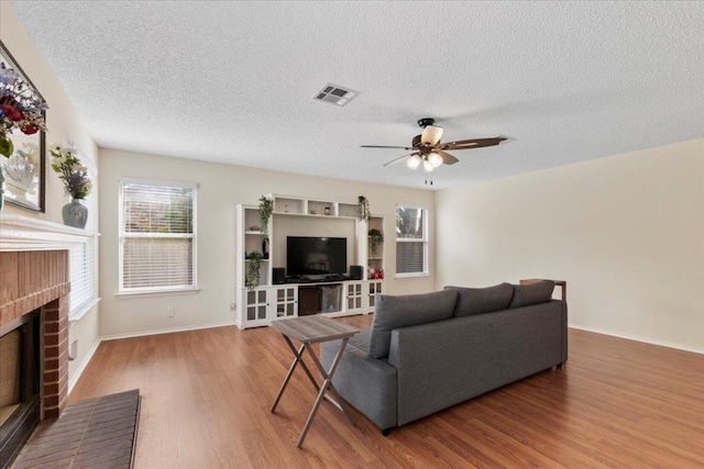 601 Wagon Wheel Trl, Pflugerville, TX 78660 - living area with wood finished floors, a fireplace, a textured ceiling, ceiling fan, and baseboards