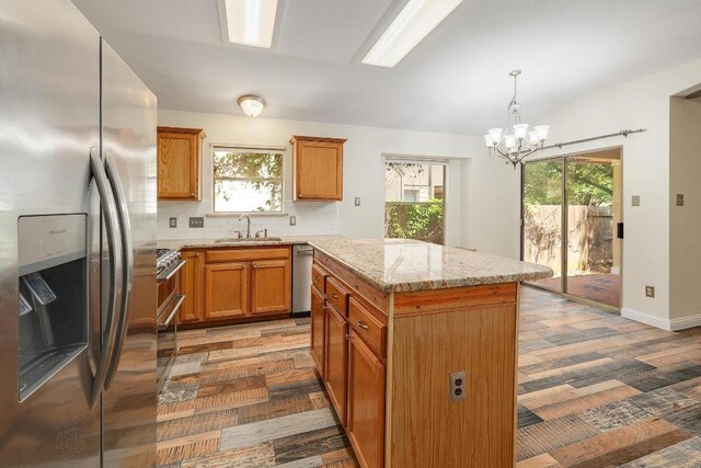 700 Horizon Trl, Cedar Park, TX 78613 - kitchen with appliances with stainless steel finishes, a kitchen island, a chandelier, light stone countertops, and brown cabinetry