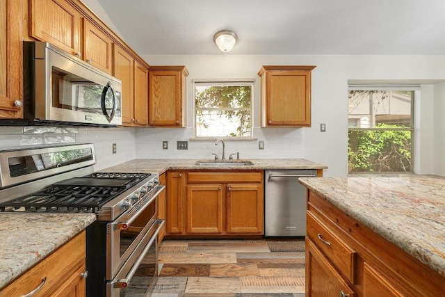 700 Horizon Trl, Cedar Park, TX 78613 - kitchen featuring appliances with stainless steel finishes, backsplash, light wood-style floors, brown cabinets, and light stone counters