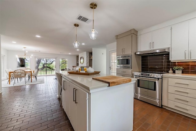928 Porpoise St, Lakeway, TX 78734 - kitchen featuring appliances with stainless steel finishes, under cabinet range hood, brick flooring, backsplash, and light countertops