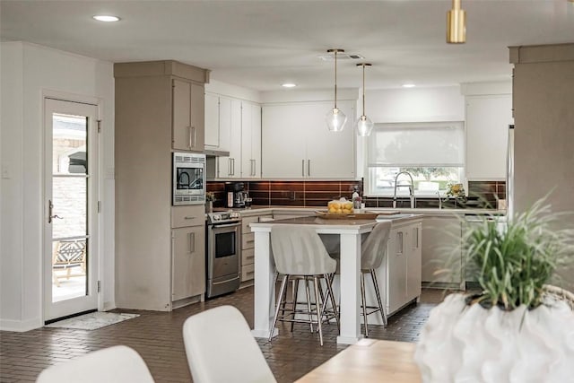 928 Porpoise St, Lakeway, TX 78734 - kitchen with appliances with stainless steel finishes, a sink, tasteful backsplash, a kitchen island, and a kitchen bar