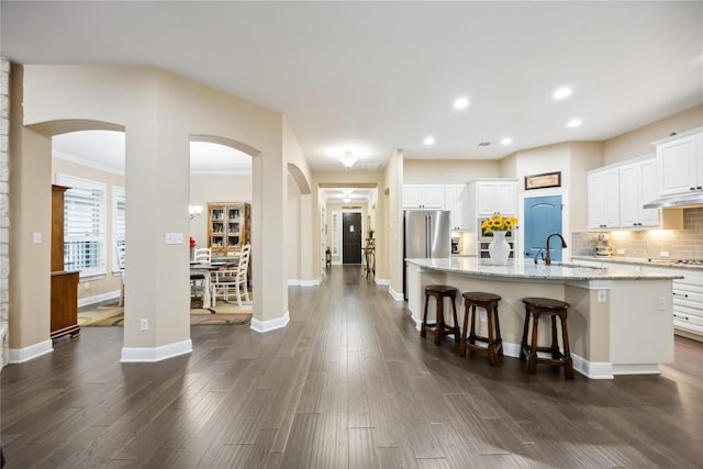 2628 Reunion Blvd, Austin, TX 78737 - kitchen with a sink, a kitchen island with sink, light stone countertops, arched walkways, and recessed lighting