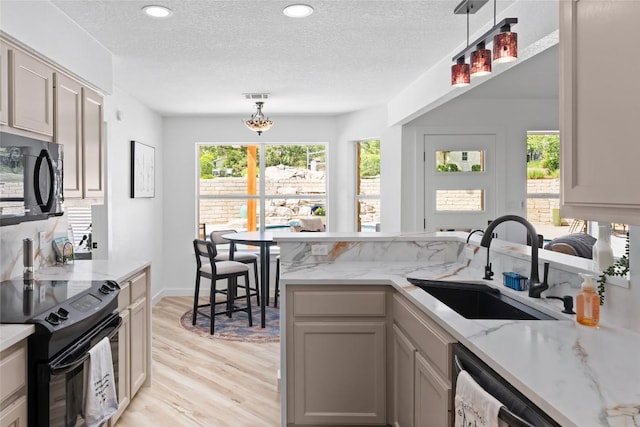 1020 Foothills Dr, Dripping Springs, TX 78620 - kitchen with black appliances, a sink, light wood-style floors, a textured ceiling, and hanging light fixtures