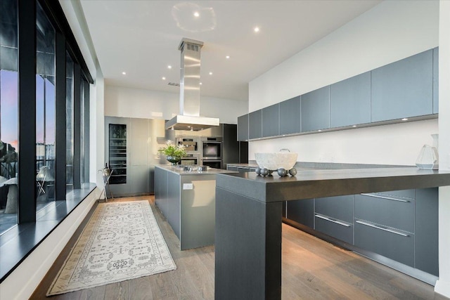 210 Lavaca St Unit 3603, Austin, TX 78701 - kitchen with a center island, modern cabinets, island exhaust hood, and light wood-type flooring