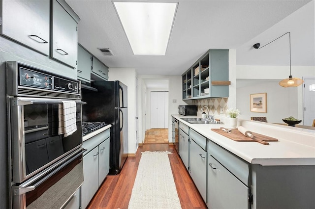 4610 S 1st St, Austin, TX 78745 - kitchen featuring dark wood finished floors, black appliances, light countertops, gray cabinets, and a peninsula