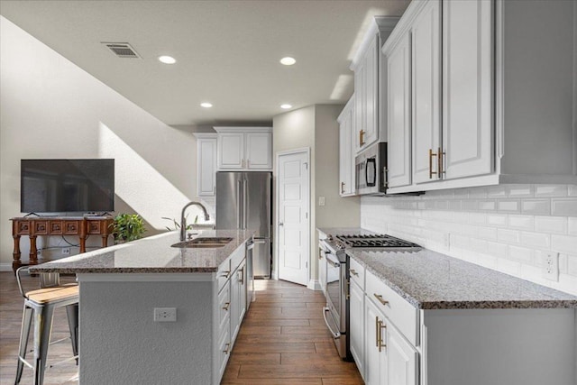 6500 Llano Stage Trl, Austin, TX 78738 - kitchen featuring stainless steel appliances, a sink, dark wood finished floors, a kitchen breakfast bar, and light stone countertops
