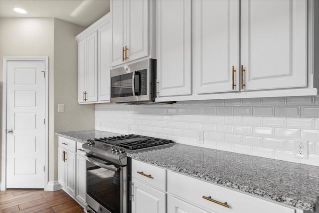 6500 Llano Stage Trl, Austin, TX 78738 - kitchen featuring appliances with stainless steel finishes, white cabinetry, tasteful backsplash, light stone countertops, and recessed lighting