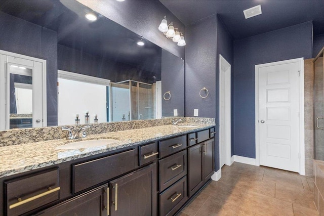 6500 Llano Stage Trl, Austin, TX 78738 - bathroom featuring a shower stall, double vanity, tile patterned floors, and baseboards