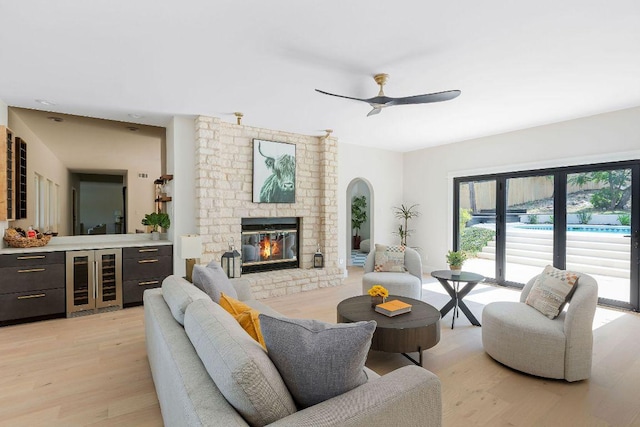 7302 Jester Blvd, Austin, TX 78750 - living room featuring beverage cooler, light wood-style flooring, ceiling fan, a fireplace, and arched walkways