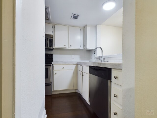 2104 Cullen Ave Unit 117, Austin, TX 78757 - kitchen with stainless steel appliances, light countertops, dark wood-type flooring, a sink, and white cabinets