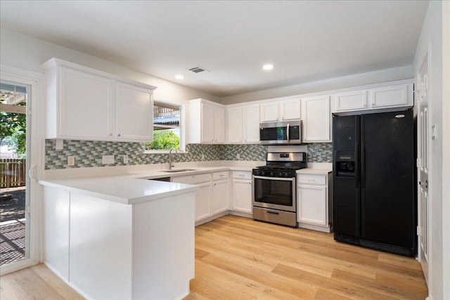1025 Doras Dr, Pflugerville, TX 78660 - kitchen featuring stainless steel appliances, light wood-style floors, white cabinets, decorative backsplash, and recessed lighting