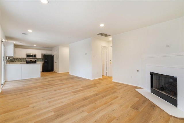 1025 Doras Dr, Pflugerville, TX 78660 - unfurnished living room featuring recessed lighting, light wood-style floors, and a tile fireplace